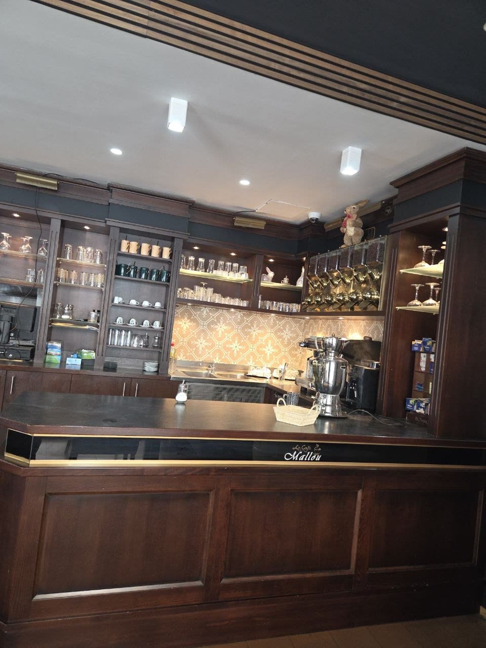 Der Café-Bereich im hinteren Teil: dunkles Holz, Messingkannen und Gläser in beleuchteten Regalen